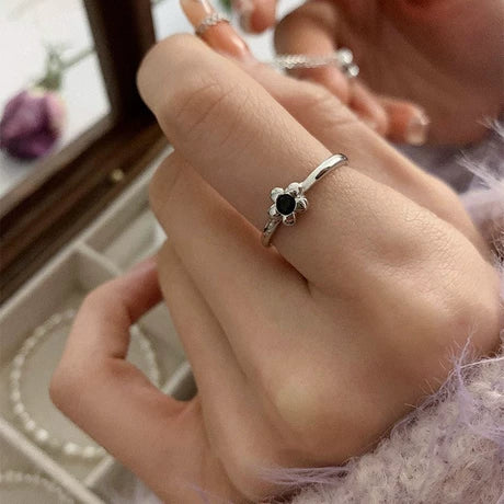 Dainty silver plated ring featuring a small four petal flower charm with a black center stone